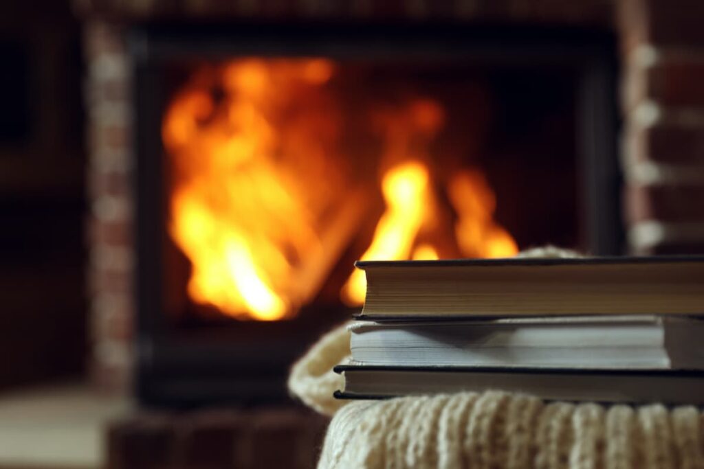 Books stacked near a cozy fire.