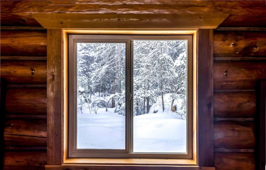 A winter scene through the window in a log cabin.