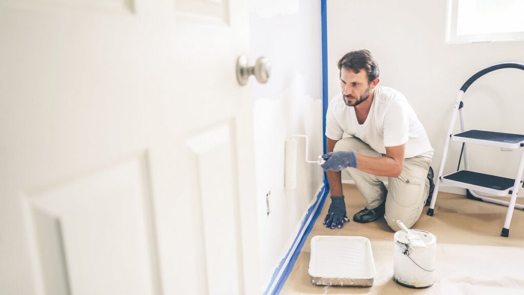 Painter carefully painting an interior wall.